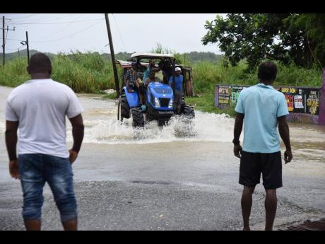 A tractor transports residents of communities surrounding Golden Grove in St Thomas, stranded after heavy rains left the community flooded.