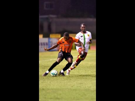Justin Dunn (left) of Tivoli Gardens FC dribbles away from  Afeba Chambers of Humble Lion F.C.    during their  Jamaica Premier League match at the Stadium East field yesterday. Dunn scored twice as Tivoli whipped Humble Lion 4-1. 