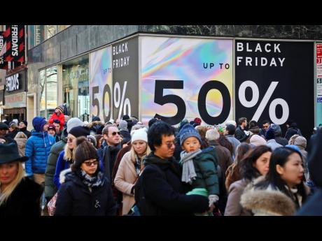 Crowds walk past a large store sign displaying a Black Friday discount in midtown Manhattan, Friday on November 23, 2018, in New York. 