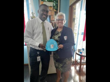 Chairman of the St George’s College Sports Council Lascelle Powell presents Principal of St George’s College Margaret Campbell with the unique and much-talked-about STGC Light Blue Helmet.