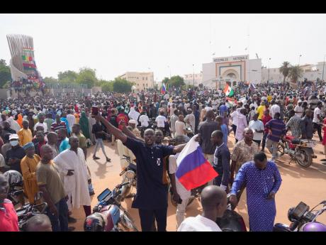 Nigeriens, some holding Russian flags, participate in a march called by supporters of coup leader General Abdourahmane Tchiani in Niamey, Niger.