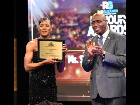 Credit: Ian Allen Gary Allen (right), Chairman of the RJRGLEANER Communications Sports Foundation, claps in honour of Shericka Jackson, who won the RJRGLEANER Honour Awards in September.