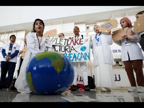 A woman pretends to resuscitate the Earth during a demonstration at the COP28 UN Climate Summit in Dubai.