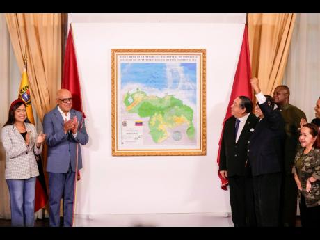National Assembly President Jorge Rodriguez (left) and Chairman of the Special Commission for the Defence of Guyana Essequibo, Hermann Escarra, along with fellow legislators, applaud after unveiling Venezuela’s new map that includes the Essequibo territo