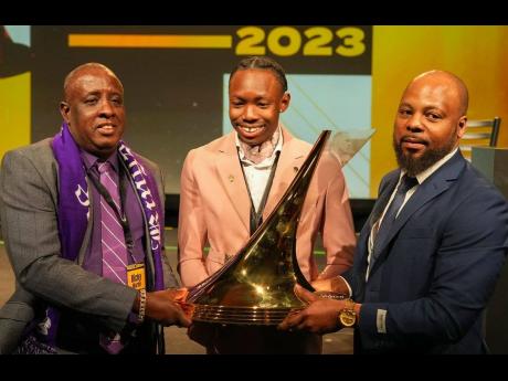 Mervin Hibbert (right) and his son, triple jumper, Jaydon Hibbert (centre), share a moment with the Bowerman Award, the latter won at the US Track & Field and Cross-Country Coaches Association Convention in Denver, Colorado on Thursday night with the champ