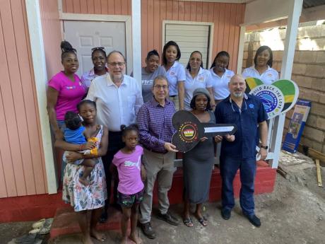 Mark Golding (fifth left), member of parliament for South St Andrew and Andrew Mahfood (seventh right), chairman of Food For the Poor (FFP), with Deneesha White (holding key), representatives of FFP, White’s family and volunteers outside her newly constr