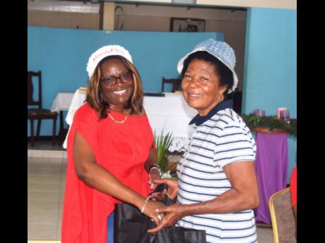 Credit: Contributed SAJ Operations Manager – Member Services, Dionne Mason-Gordon (left), presents a care package to an elderly resident of the Greenwich Farm community.