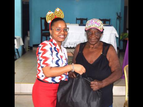 Credit: Contributed Caribbean Shipping Association administrative and training coordinator Sonya Hall (left) is all smiles as she presents a care package to this Greenwich Farm resident.