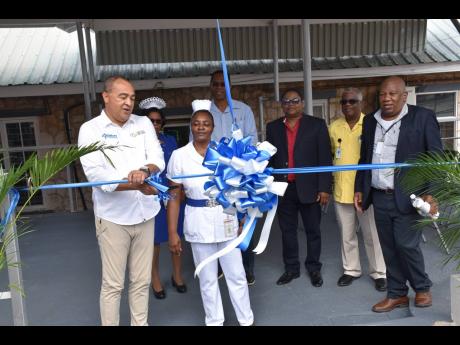 Minister of Health and Wellness Dr Christopher Tufton cuts the ribbon to open the newly refurbished waiting area at the Mandeville Regional Hospital on December 14. Beside him is Nurse Janett Bonner-Waugh. Others in the background (from left) are Matron Sa