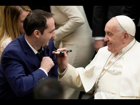 Pope Francis autographs the suit of a newly wed groom during his weekly general audience in the Pope Paul VI hall at the Vatican.