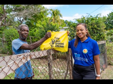 Michelle Lawe, human resource manager, Jamaica Broilers Group, presents a Best Dressed Chicken goodie bag filled with groceries to McCook’s Pen resident, Gerald Wilson, at The Best Dressed Chicken’s annual Christmas outreach to the elderly and indigent