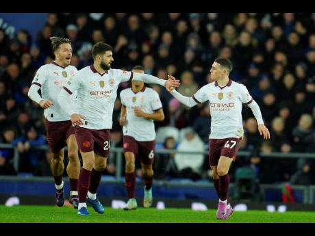 Manchester City’s Phil Foden (right) is congratulated after scoring his side’s first goal during an English Premier League football match against Everton at Goodison Park in Liverpool, England, yesterday.
