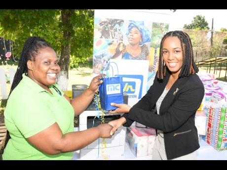 Lexy-Ann Hudson (right), sales administrator at MC Systems, a member company of the Jamaica National Group, presents Nadia Williams, administrator of Mary’s Child, with a printer during the Christmas holiday. The printer will facilitate the printing of s