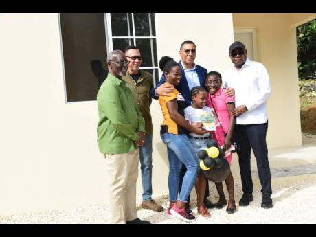 Norma Cooper (centre) and her daughter Tresha-Gay Rattray (right) lead Prime Minister Andrew Holness on a tour of her new home. The one-bedroom house was presented to her yesterday under the Government’s social housing programme. 