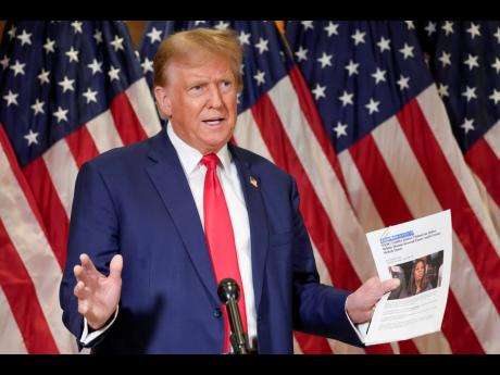 Former President Donald Trump holds up a copy of a story featuring New York Attorney General Letitia James while speaking during a news conference.