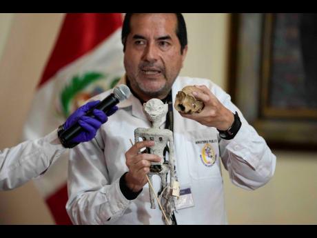 Forensic archaeologist Flavio Estrada from Peru's prosecutor's office shows a doll, which was seized by authorities before it was shipped to Mexico, during a press conference to explain what it is made of at the Archaeology Museum in Lima, Peru, Friday, Ja
