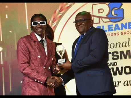 
World champion 400-met runner Antonio Watson (left) receives the People’s Choice Award from RJRGLEANER Chief Executive Officer Anthony Smith during the RJRGLEANER Sportsman and Sportswoman Awards Ceremony at The Jamaica Pegasus hotel on Friday Night.