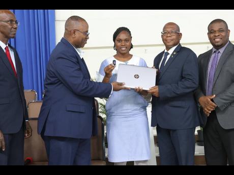 Shavay Shearer (centre), Northern Caribbean University (NCU) final-year nursing student, receives her laptop and oximeter from Nurse Owen Gregory (second left), senior international heritage liaison for AdventHealth, while Dr Lincoln Edwards (second right)