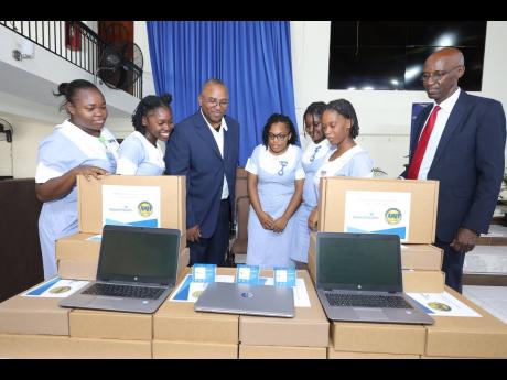  Nurse Owen Gregory, senior International heritage liaison for AdventHealth, is flanked by Northern Caribbean University (NCU) nursing students as Pastor Everett Brown (right), board chair for AMH, NCU and GSI Foundation, looks on as they examine samples o