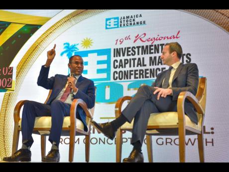 Minister of Finance and the Public Service Dr Nigel Clarke (left) responds to a question at Wednesday’s session of the Jamaica Stock Exchange Investments and Capital Markets Conference at The Jamaica Pegasus hotel in New Kingston. At right is head of Lat