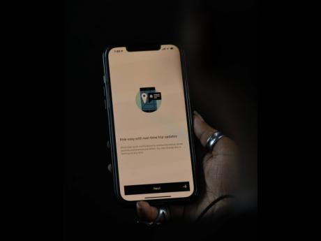 A commuter uses the popular Uber app to seek a ride in Jamaica.