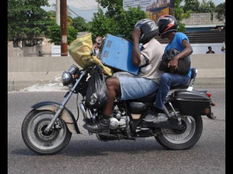 In this 2015 photo a motorcyclist and the pillion rider are seen loaded with goods.