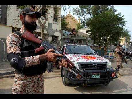 Paramilitary soldiers stand guard on the side of a road for security, ahead of the February 8 general elections, in Karachi, Pakistan, Wednesday.