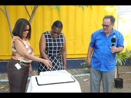 Dr Karyl Powell-Booth (left), lecturer, School of Allied Health and Wellness, College of Health Sciences, cuts the celebratory cake with Darcy Tulloch-Williams (centre), executive director, Mustard Seed Communities. Sharing in the photo is Anthony Brodber,