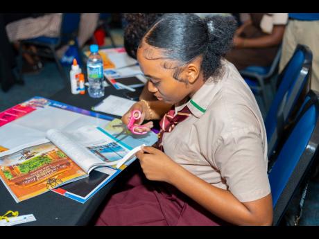 Shakeila Cummings, a student from Godfrey Stewart High, is seen cutting out images to include on her 2024 vision board.