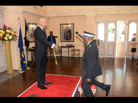 Clembert Powell, Knight of Grace, kneels before Governor General and President of the National Council of the St John Association of Jamaica, Sir Patrick Allen, to receive his knighthood during a promotion and investiture ceremony at King’s House in 2019