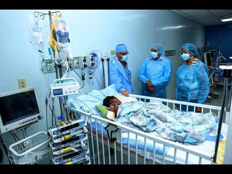  From left: Surgeon, Professor Jeff Jacobs; Christopher Zacca, chairman of the Sagicor Foundation; and Diane Edwards, chairman, Chain of Hope, visit a young patient at the Bustamante Hospital for Children’s Cardiac Centre.