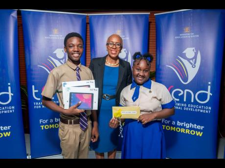 Minister of Education and Youth Fayval Williams (centre) shares a congratulatory embrace with team lead Javon Johnson, the second-place winner and fifth-form student of Kingston College, alongside Javaugn Davidson and Dantae Williams (not in picture); as w