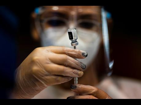 FILE - A nurse prepares a dose of the Pfizer COVID-19 vaccine at the Tomas Dones Coliseum, in Fajardo, Puerto Rico, Jan. 8, 2022.