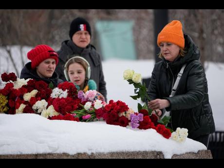 A woman lays flowers to pay the last respect to Alexei Navalny at the monument, a large boulder from the Solovetsky islands, where the first camp of the Gulag political prison system was established, near the historical the Federal Security Service (FSB, S