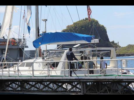 Investigators from Grenada and St Vincent and the Grenadines stand aboard the yacht ‘Simplicity’, that they say was hijacked by 3 escaped prisoners with two people aboard, now anchored at the St Vincent and the Grenadines Coastguard Service Calliaqua B