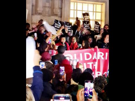 Hackney North MP Diane Abbott (with microphone) is cheered as she attended a protest in support of her outside Hackney Town Hall on Friday.