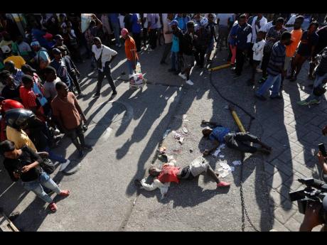 EDS NOTE: GRAPHIC CONTENT - The bodies of two people lie on the street after an overnight shooting in the Petion Ville neighborhood of Port-au-Prince, Haiti, Monday, March 18, 2024. (AP Photo/Odelyn Joseph)