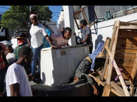 People look at a body after an overnight shooting in the Petion Ville neighbourhood of Port-au-Prince, Haiti, Monday, March 18, 2024. 