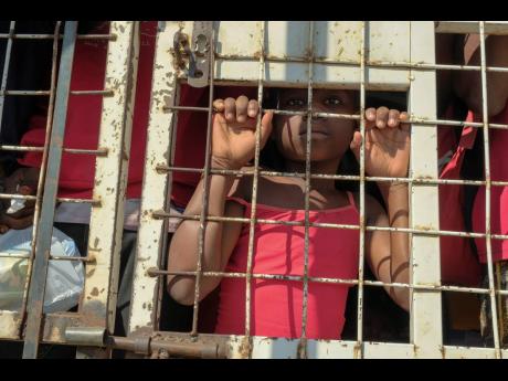 A child stands amid people who were detained for deportation to Haiti inside a police truck on a border bridge that connects Dajabon, Dominican Republic with Haiti, Monday, March 18, 2024. (AP Photo/Ricardo Hernandez)