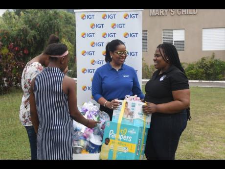 Debbie-Ann Green (second right), general manager, International Game Technology (IGT), presents care packages for young mothers to Nadia Williams (right), administrator at Mustard Seed Communities, Mary’s Child on February 27 in honour of International W