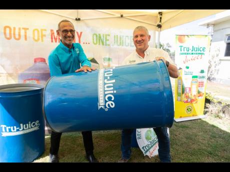 Dr Damien King (left), chairman of Recycling Partners of Jamaica (RPJ) and Peter McConnell, managing director of Trade Winds Citrus, show off one of the 600 drums donated by Tru Juice to RPJ during a handing over ceremony at Trade Winds Citrus on March 15.