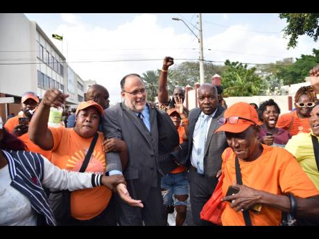 Credit: Antoine Lodge Members of the Jamaica Constabulary Force assist Opposition Leader Mark Golding through a crowd of People’s National Party supporters on the outskirts of Parliament on Tuesday.