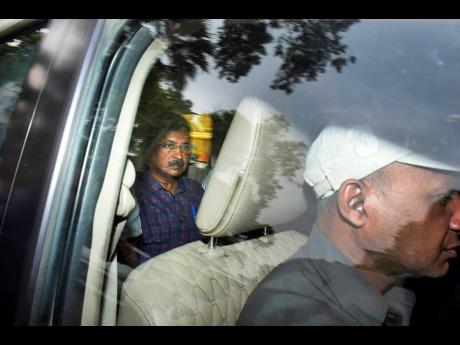 Arvind Kejriwal (left), leader of the Aam Admi Party, or Common Man’s Party, leaves in a car after attending a hearing at a court in New Delhi, India, on March 28. 
