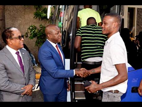 Minister of Labour and Social Security, Pearnel Charles Jr (second left), bids farewell to a participant in the Seasonal Agricultural Workers Programme (SAWP), during a ceremony held at the Overseas Employment Centre, East Street, Kingston, on January 3. A