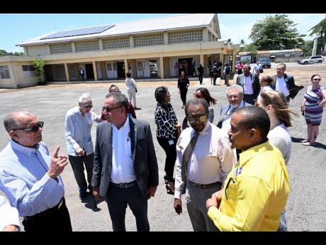 Kevin Mills (right) of Renewable Energy Design and Installation Services Ltd shows solar panels of the PV and PV+ system for the Central Village Multipurpose Centre, with N. Nick Perry (second right), ambassador of the United States to Jamaica; James Rawle