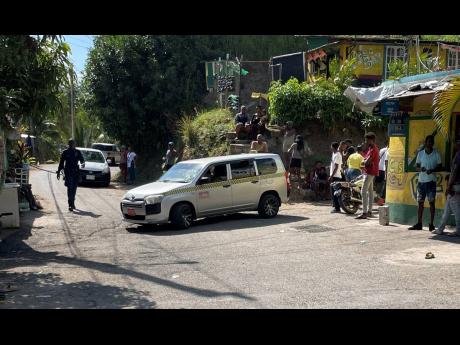 Residents gather in Burnt Shop square in Lawrence Tavern, St Andrew, on Monday morning after three men were shot and seriously injured in a drive-by shooting.
