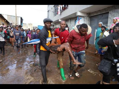 Residents rescue a woman who was caught during heavy rain in the Mathare slum of Nairobi, Kenya, on Wednesday.