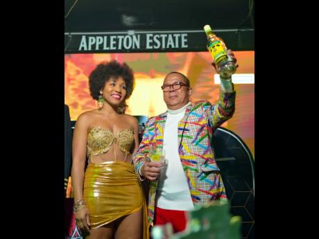 Credit: Contributed Attorney-at-law Roshania Howard (left), wearing a cutout gold mini, and Brian ‘Ribbi’ Chung share a toast with the gathering.