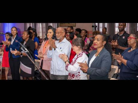 The audience inside the Lecture Hall of the Institute of Jamaica in downtown gives Dr Pauline Mullings a standing ovation after she announcement her decision to reliquish the role of chairman of the National Child Month Committee and pass the baton to Nico