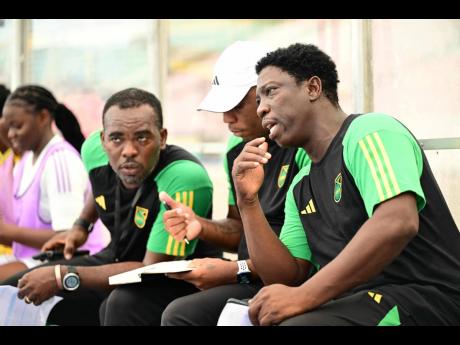 
Reggae Girlz head coach Xavier Gilbert (right) in conversation with staff.